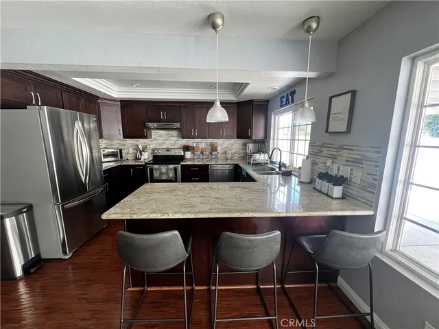 a living room with stainless steel appliances furniture a rug and a large window
