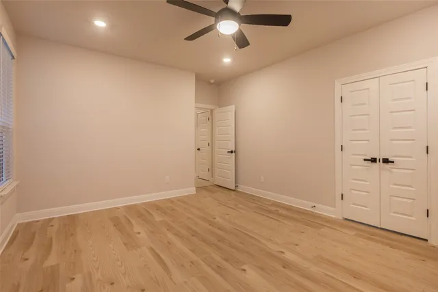 an empty room with closet and a ceiling fan