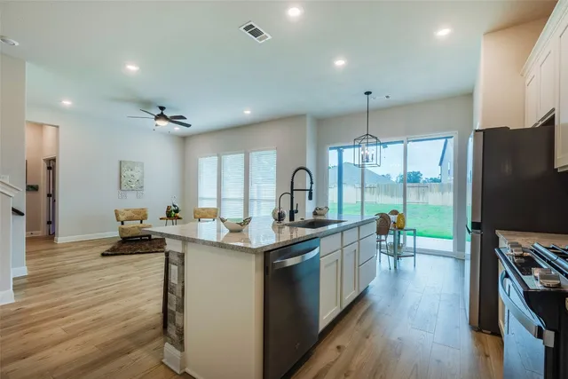 a kitchen with stainless steel appliances a sink stove and wooden floor