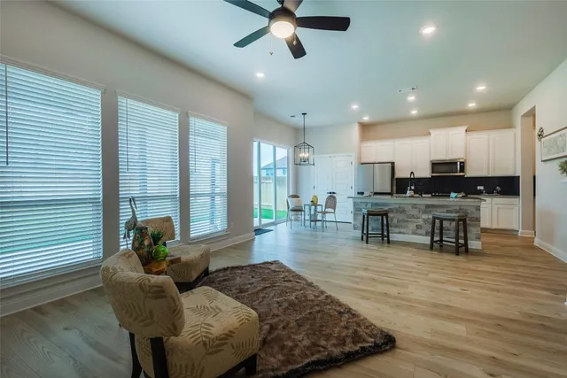 a living room with furniture and kitchen view with a large window