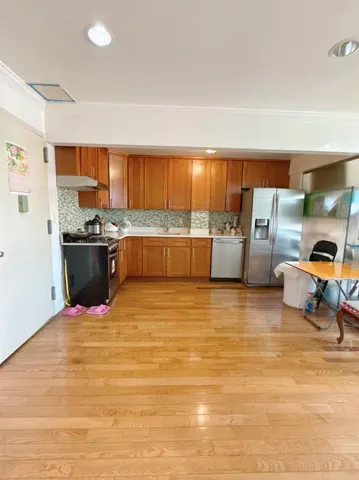 a kitchen with stainless steel appliances wooden floor and view living room