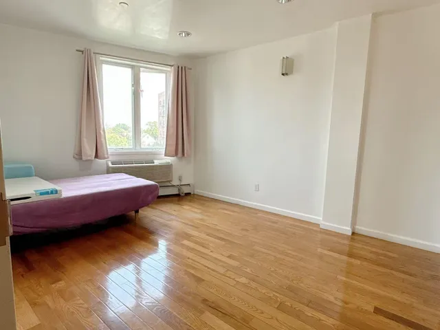 a spacious bedroom with a bed and wooden floor