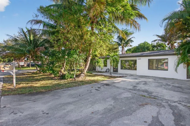 a view of a house with a yard and palm trees