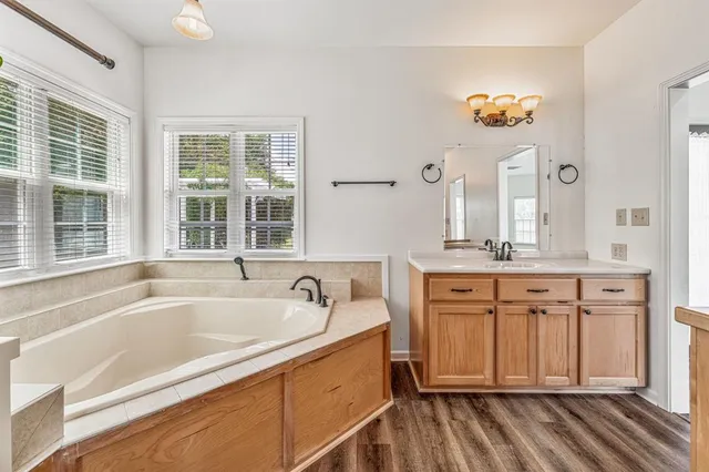 a spacious bathroom with a tub sink and mirror