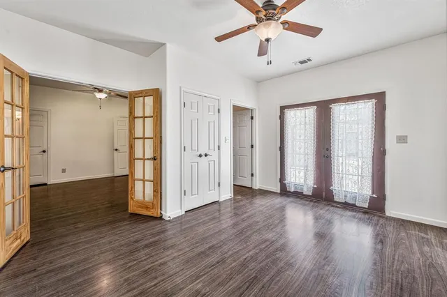 an empty room with wooden floor fan and windows