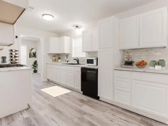 a kitchen with a sink a stove a refrigerator and white cabinets