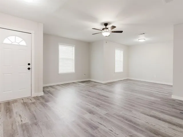 a view of an empty room with wooden floor and a window
