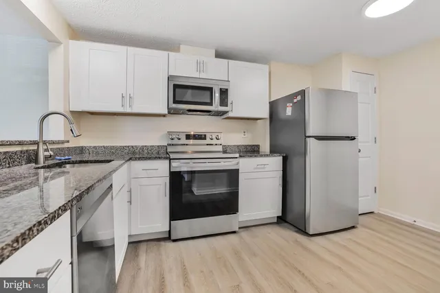 a kitchen with stainless steel appliances granite countertop a stove a refrigerator and a sink