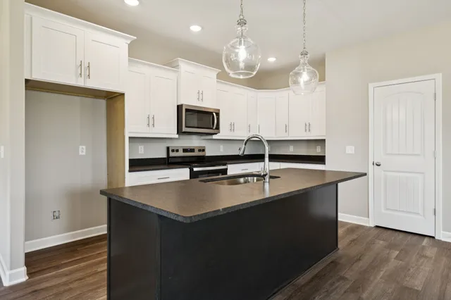 a kitchen with kitchen island granite countertop a sink a counter space appliances and cabinets
