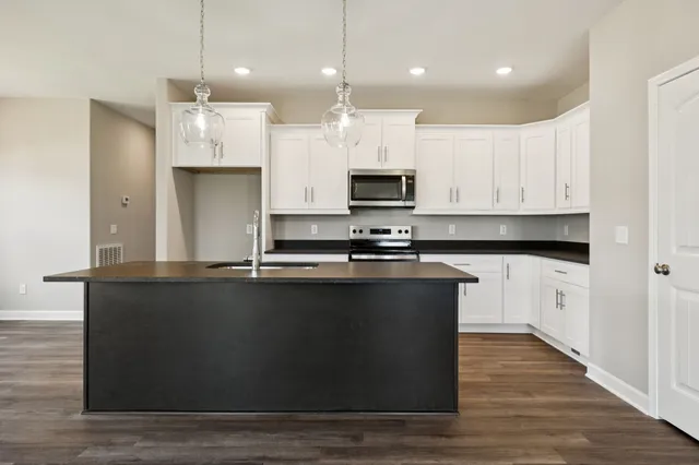 a kitchen with stainless steel appliances granite countertop a sink a stove a refrigerator and wooden floor