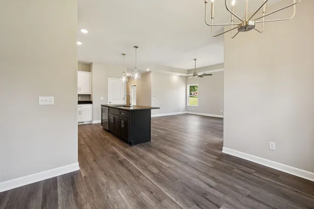 an empty room with wooden floor exposed radiator and windows