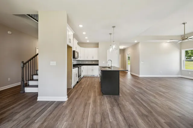 a view of a room with wooden floor a ceiling fan and windows