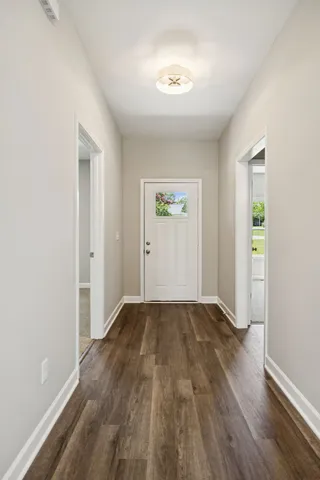 a view of an empty room with window and wooden floor