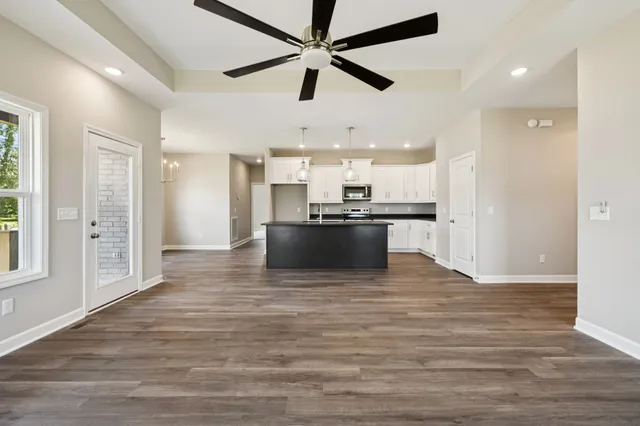 a large kitchen with stainless steel appliances a large counter top and wooden floors