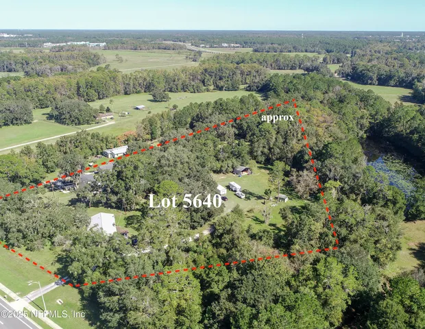 an aerial view of a houses with a yard and lake view