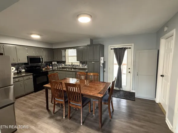 a kitchen with stainless steel appliances granite countertop a dining table chairs refrigerator and cabinets