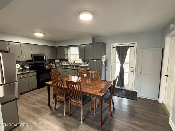 a kitchen with stainless steel appliances granite countertop a dining table chairs refrigerator and cabinets