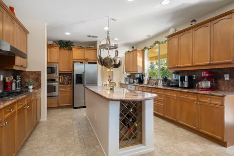 a large kitchen with stainless steel appliances kitchen island granite countertop a stove a sink dishwasher and cabinets with wooden floor