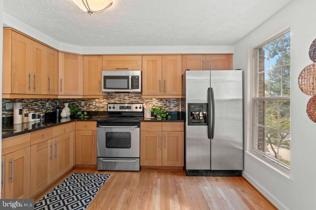 25 Capps Court Gaithersburg, MD 20878 - Photo 7 of 39 a kitchen with granite countertop a refrigerator and a stove top oven