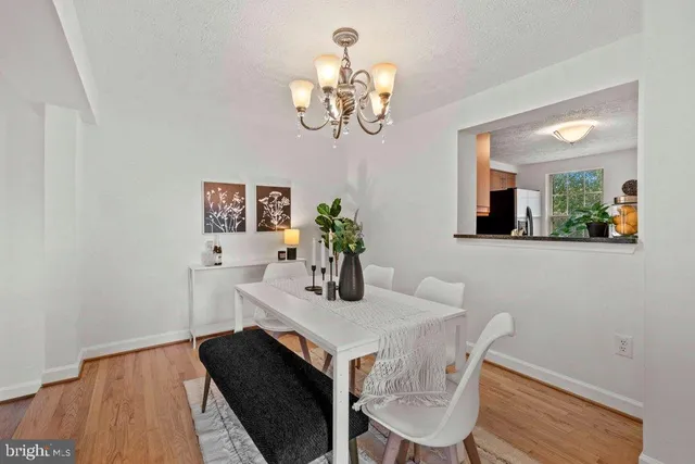 a dining room with wooden floor a chandelier a wooden table and chairs