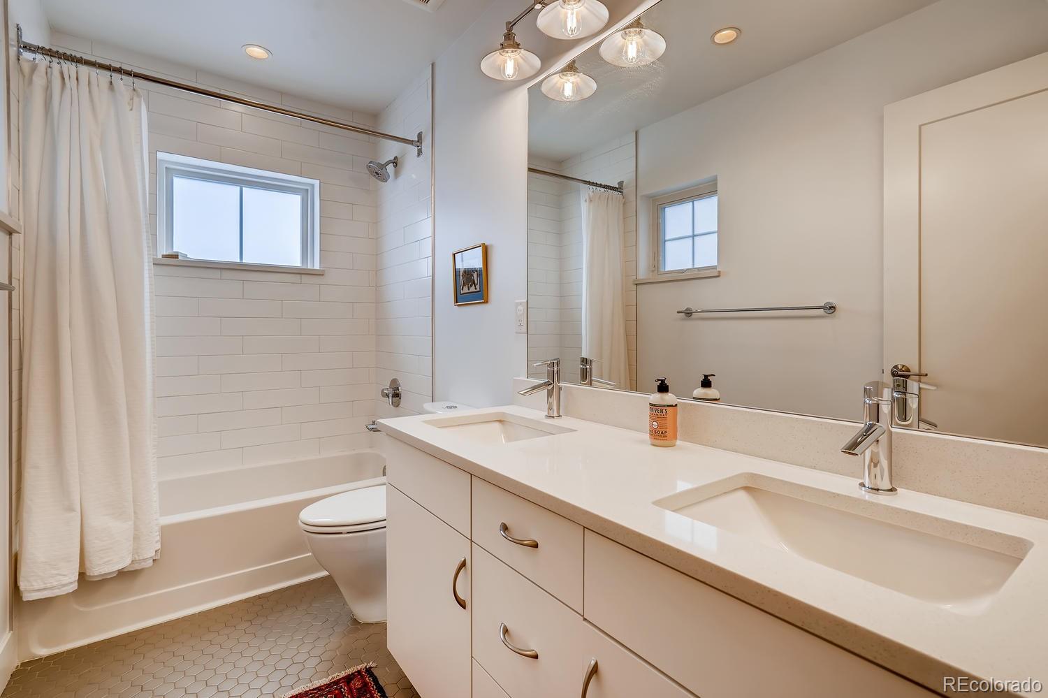 4565 Stuart Street Denver, CO 80212 - Photo 18 of 28 a bathroom with a double vanity sink toilet mirror and bathtub