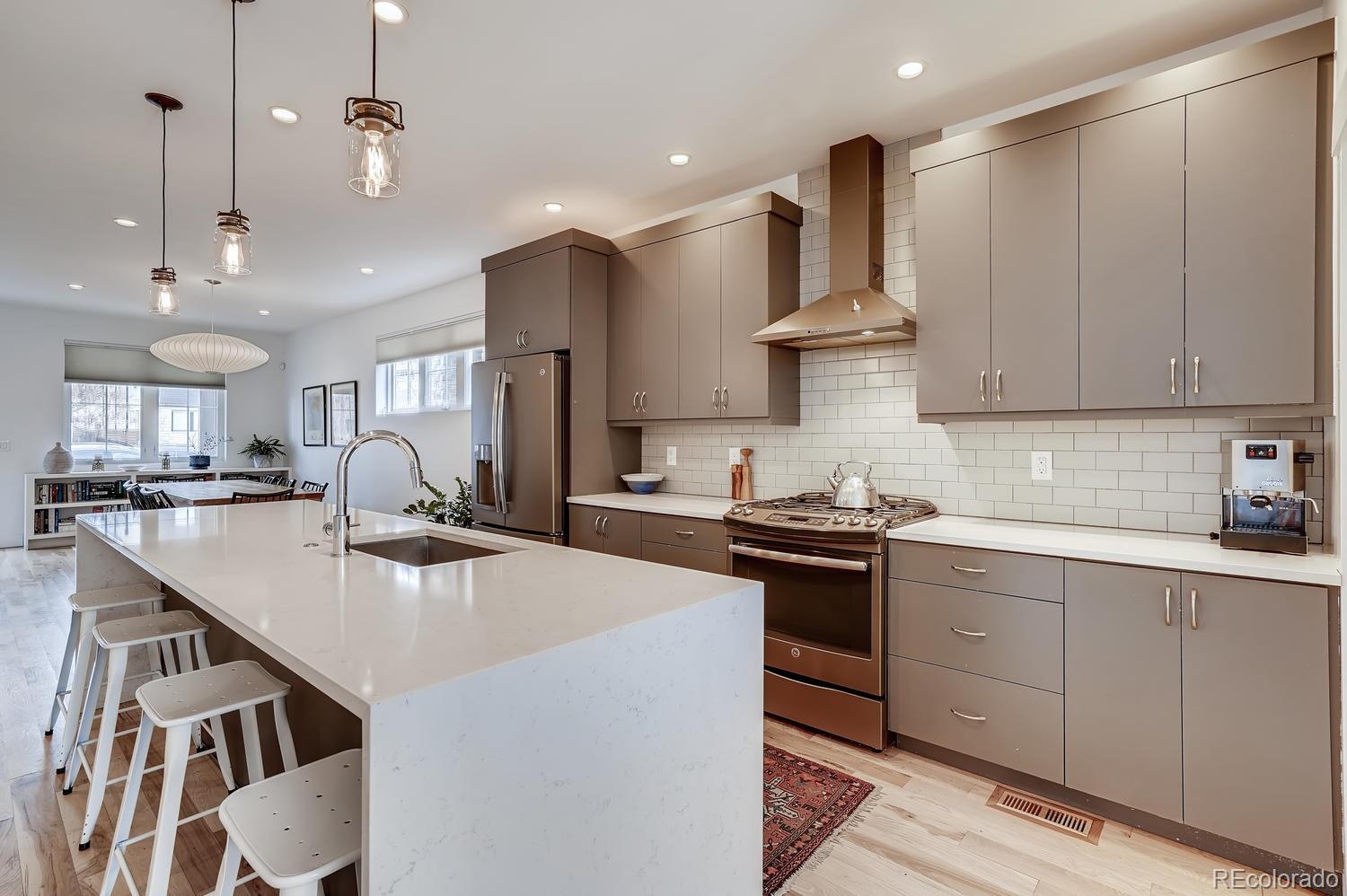 4565 Stuart Street Denver, CO 80212 - Photo 7 of 28 a kitchen with stainless steel appliances kitchen island a sink stove and cabinets