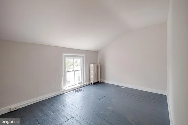 an empty room with wooden floor and window