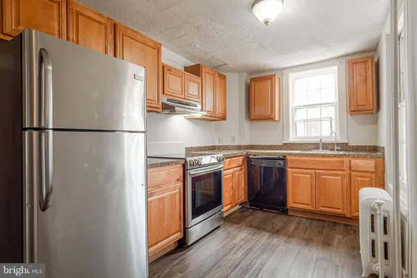 a kitchen with stainless steel appliances granite countertop a refrigerator a stove a sink and a window