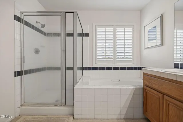 a bedroom with a bed a dresser and a large mirror next to a window