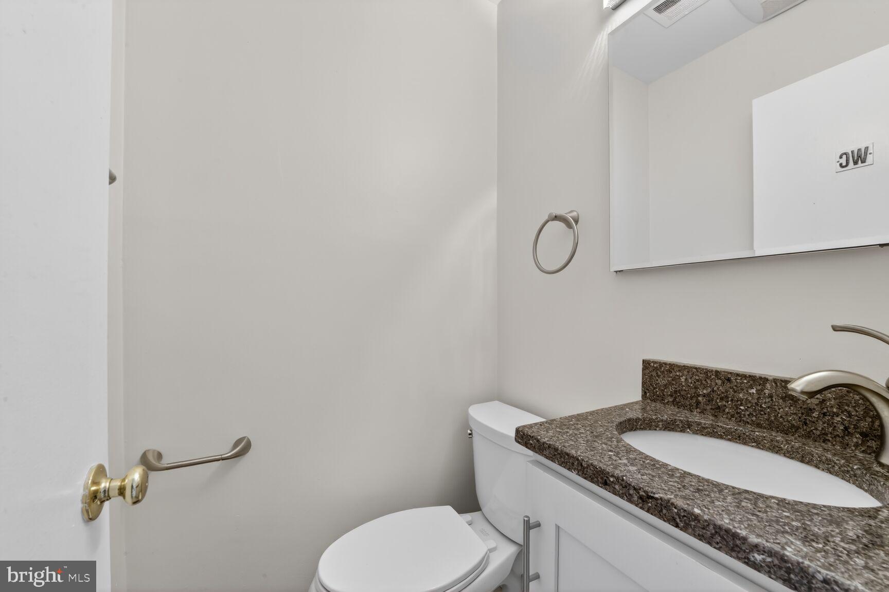 329 1/2 6th Street Southeast, Unit B Washington, DC 20003 - Photo 4 of 13 a bathroom with a granite countertop toilet sink and mirror