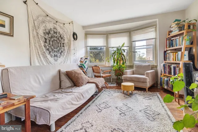 a living room with furniture and a bookshelf with wooden floor