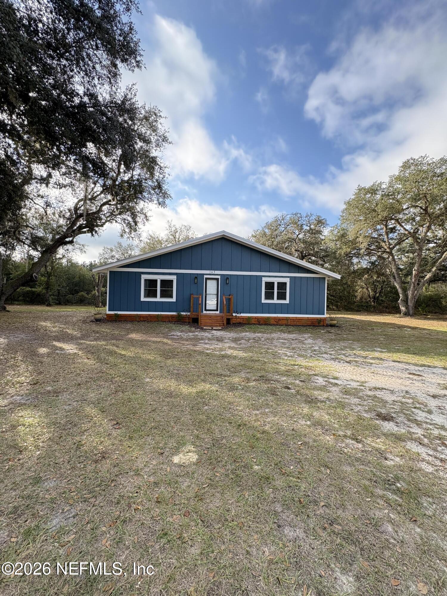 a front view of house with yard and trees around