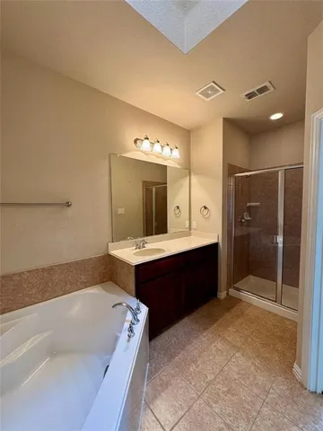 a spacious bathroom with a tub sink shower and mirror
