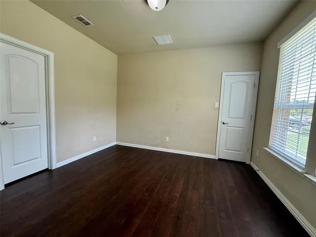 an empty room with wooden floor and windows