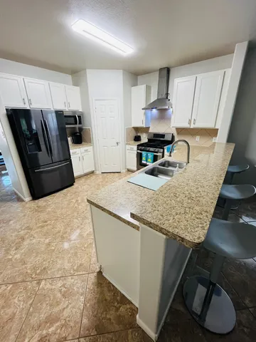 a kitchen with granite countertop a sink a stove a refrigerator and cabinets