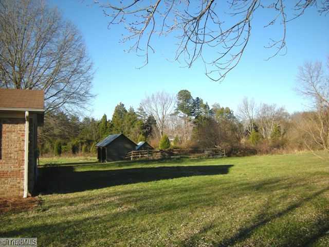 1796 Sandy Ridge Road Kernersville, NC 27284 - Photo 8 of 10 Exterior Back. view of shed, fenced area & an additional outbuilding on a private wooded lot