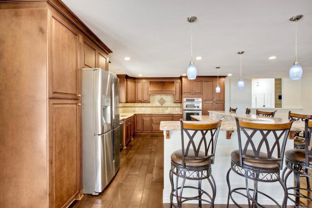 13815 Hilldale Road Valley Center, CA 92082 - Photo 14 of 50 a kitchen with stainless steel appliances a dining table chairs refrigerator and sink