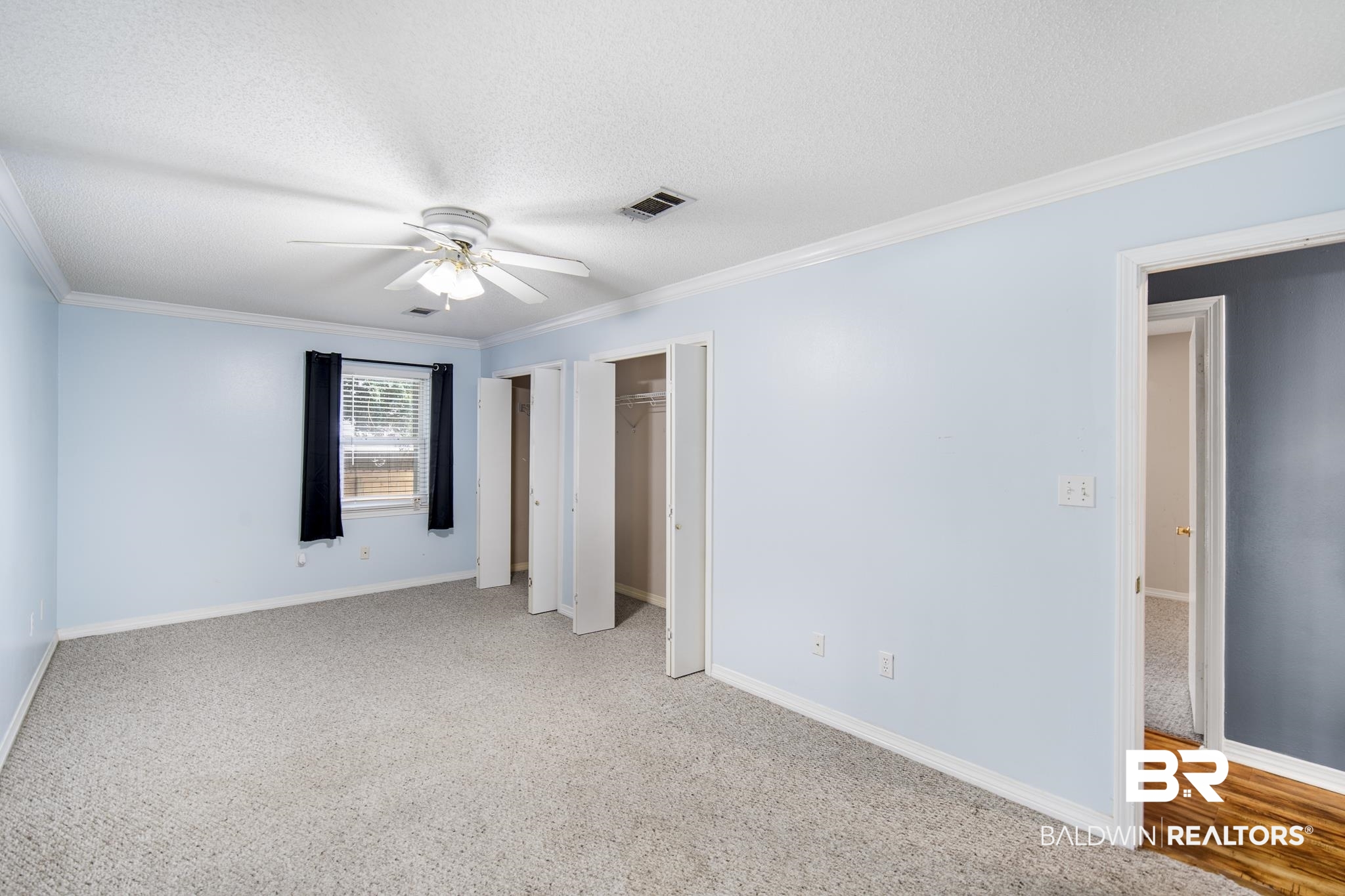 103 Ann Street Daphne, AL 36527 - Photo 12 of 23 Unfurnished bedroom with two closets, ornamental molding, a ceiling fan, carpet, and a textured ceiling
