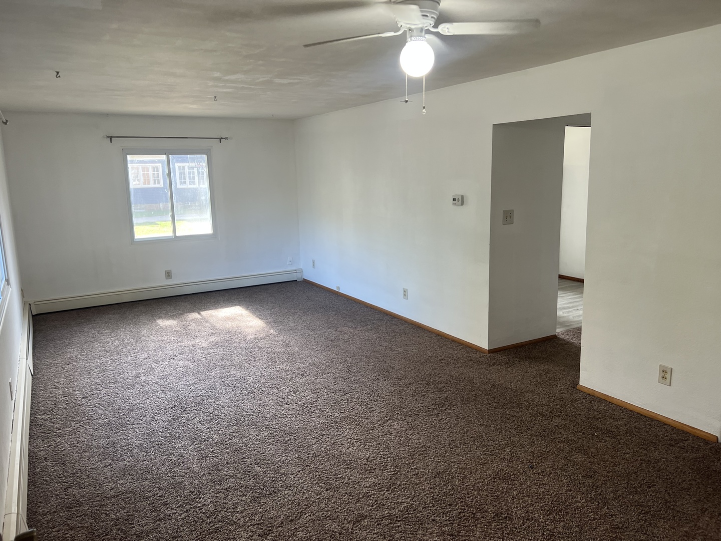 301 North Minier Avenue, Unit 1 Minier, IL 61759 - Photo 2 of 7 an empty room with a chandelier fan and windows