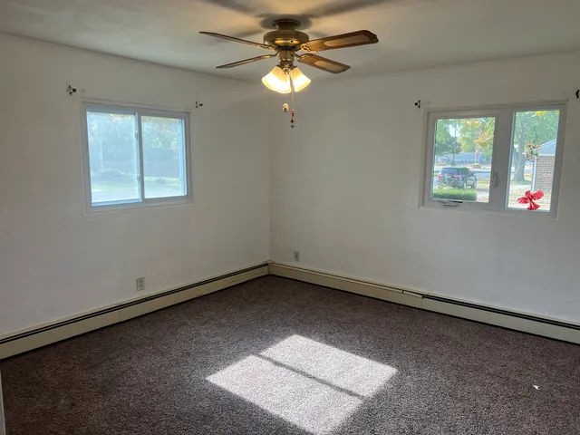 an empty room with windows and fan
