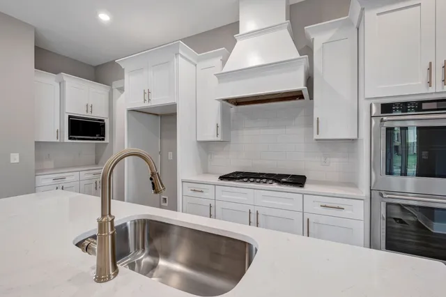 a kitchen with stainless steel appliances granite countertop a sink a stove and a refrigerator