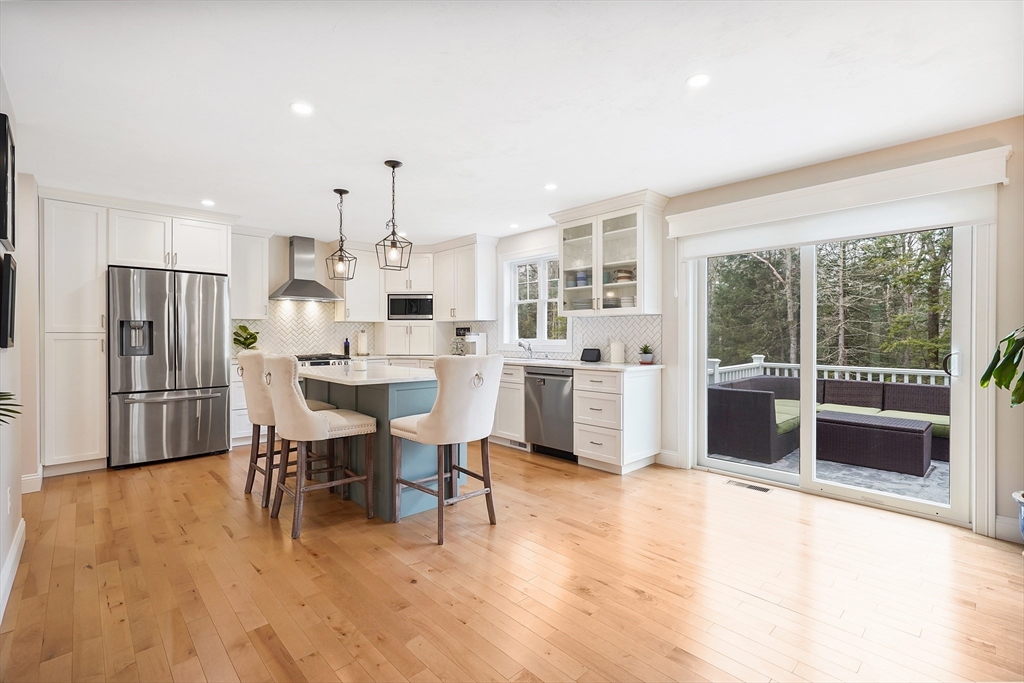 61 New Boston Road Sturbridge, MA 01566 - Photo 12 of 42 a large white kitchen with stainless steel appliances kitchen island granite countertop a dining table chairs and granite counter tops