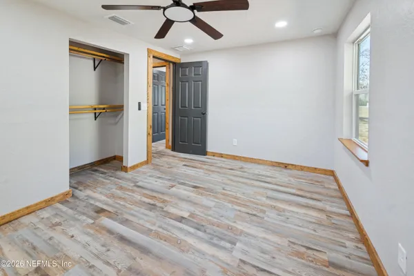 a view of empty room with wooden floor and fan