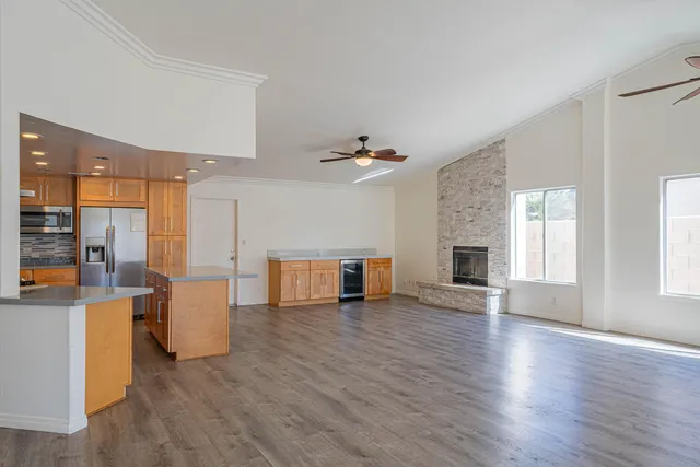 a kitchen with stainless steel appliances granite countertop a refrigerator a sink and a stove with wooden floor