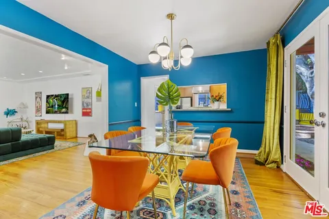 a dining room with wooden floor a chandelier a glass table and chairs
