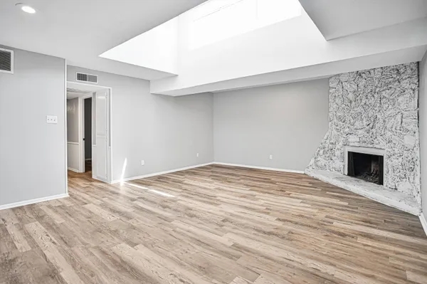 an empty room with wooden floor fan and windows