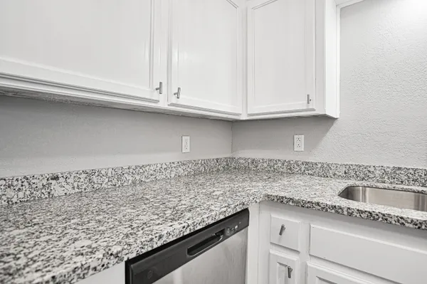 a kitchen with granite countertop a sink and a white cabinets