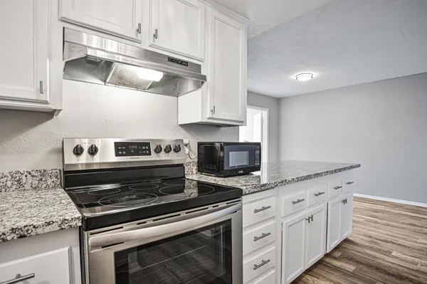 a kitchen with granite countertop white cabinets and white appliances