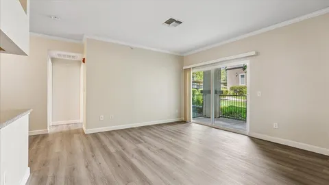 a view of an empty room with a window and wooden floor