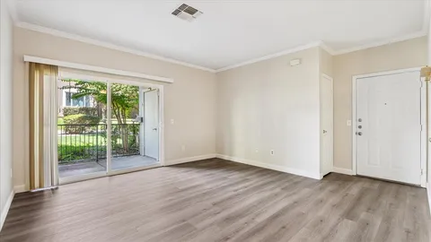 a view of empty room with wooden floor and fan